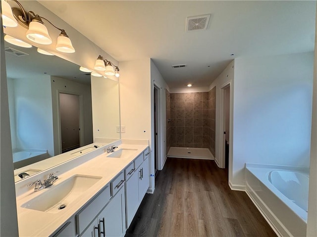 full bath with wood finished floors, a sink, and visible vents