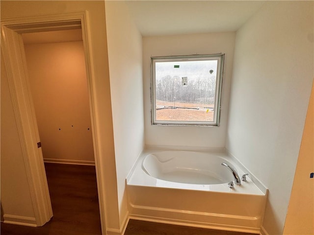 bathroom featuring baseboards, a bath, and wood finished floors