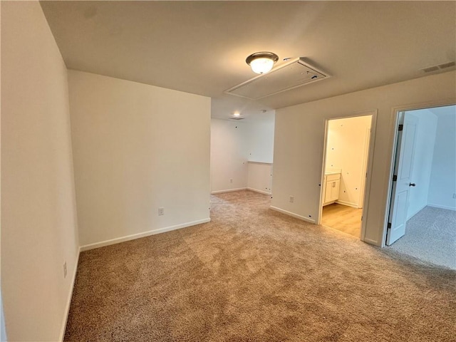 spare room featuring attic access, visible vents, light carpet, and baseboards