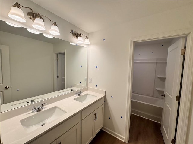 full bath featuring double vanity, wood finished floors, and a sink