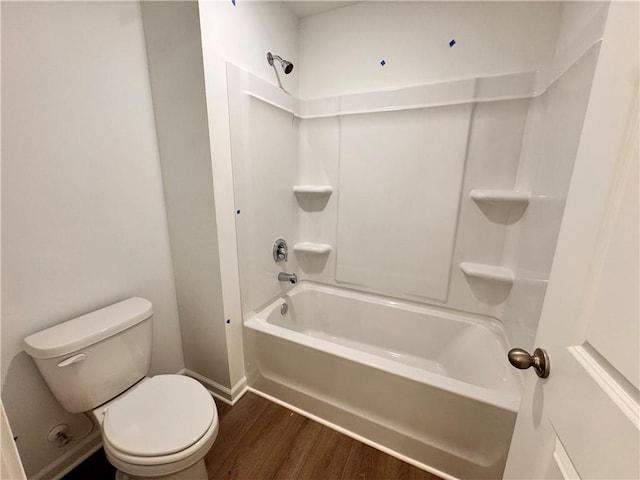 full bathroom with toilet, washtub / shower combination, baseboards, and wood finished floors