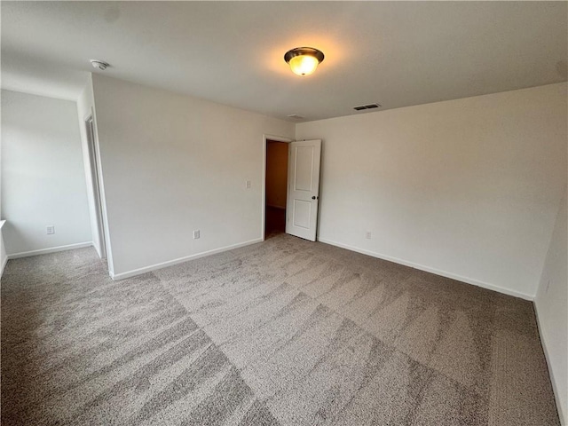 carpeted spare room featuring visible vents and baseboards