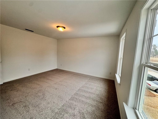 unfurnished room featuring carpet, visible vents, and baseboards