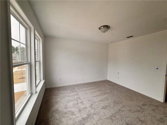 spare room featuring carpet, visible vents, and baseboards