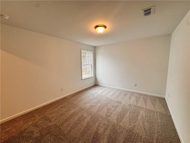 empty room with carpet, visible vents, and baseboards