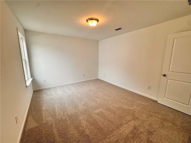 carpeted spare room featuring baseboards and visible vents