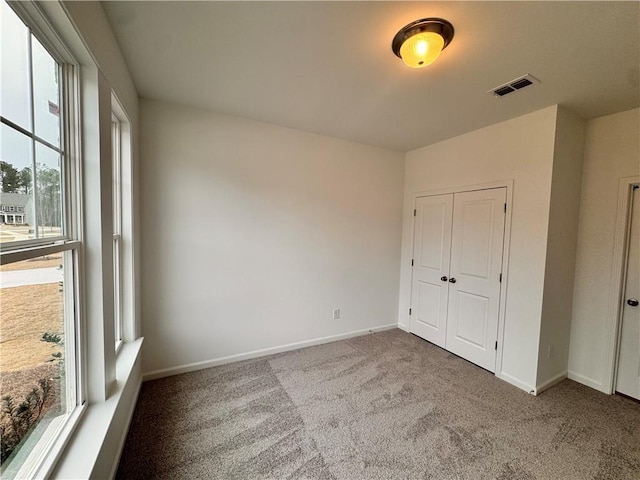 unfurnished bedroom featuring a closet, baseboards, visible vents, and carpet flooring