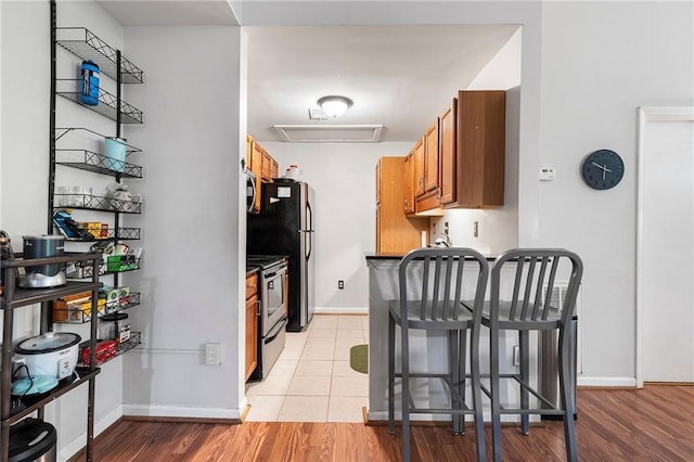 1031 State St NW Unit 106, Atlanta, GA 30318 - kitchen with appliances with stainless steel finishes, brown cabinets, baseboards, and light wood-type flooring