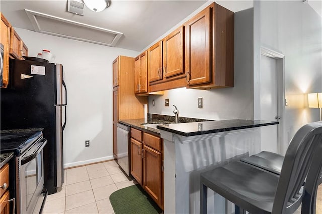 1031 State St NW Unit 106, Atlanta, GA 30318 - kitchen featuring stainless steel appliances, a sink, a kitchen breakfast bar, brown cabinetry, and dark stone countertops