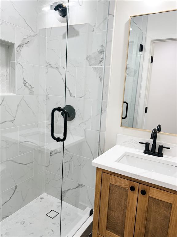 bathroom featuring walk in shower and vanity