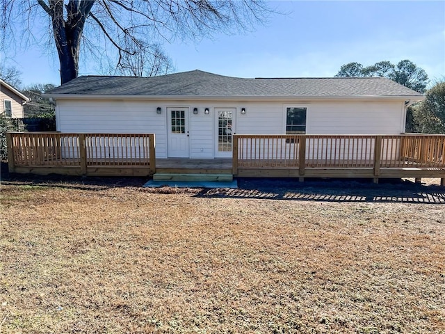 rear view of property featuring a wooden deck and a lawn