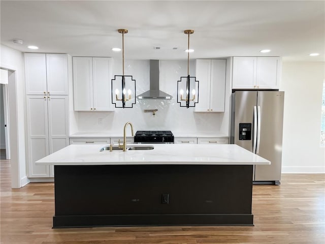 kitchen featuring pendant lighting, sink, stainless steel fridge, white cabinetry, and wall chimney exhaust hood