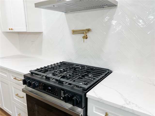 kitchen featuring light stone counters, tasteful backsplash, custom range hood, white cabinets, and gas range