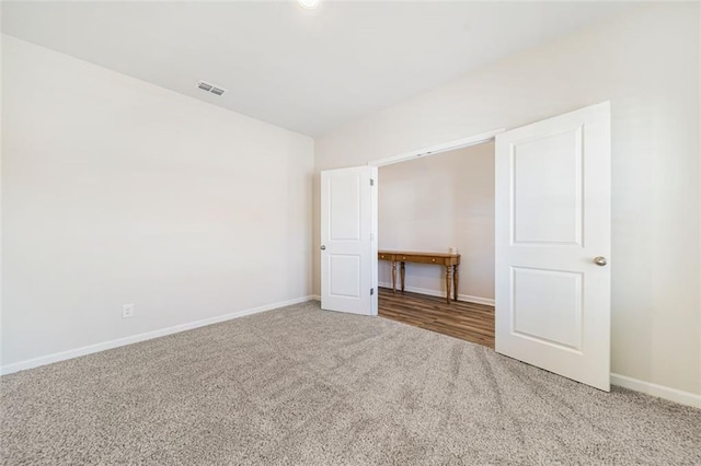 spare room featuring visible vents, baseboards, carpet flooring, and vaulted ceiling