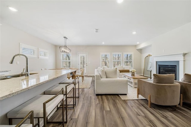 living area featuring a glass covered fireplace, visible vents, recessed lighting, and dark wood-style flooring