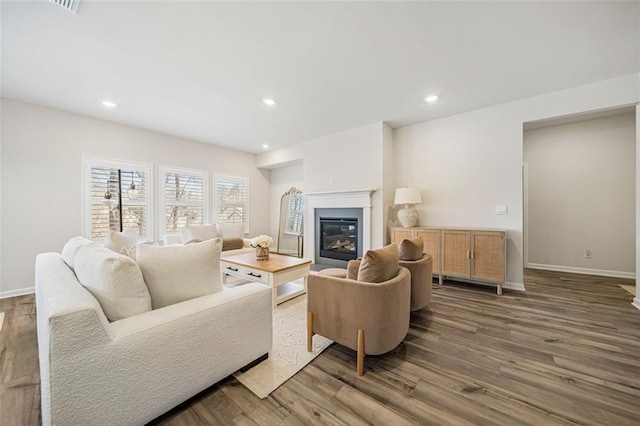 living room with a glass covered fireplace, baseboards, and wood finished floors