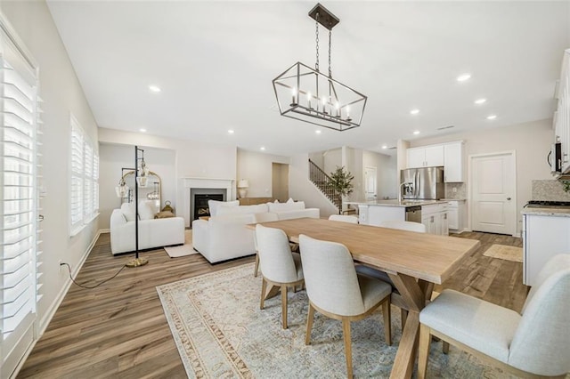 dining area featuring recessed lighting, stairs, wood finished floors, and a fireplace