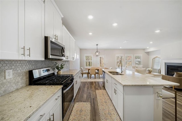 kitchen with a sink, stainless steel appliances, dark wood-type flooring, white cabinetry, and backsplash