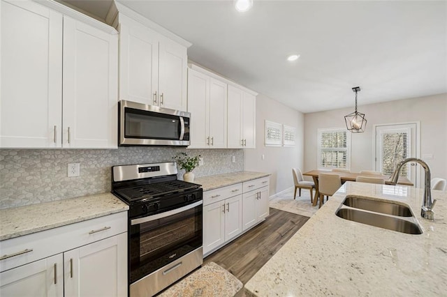 kitchen featuring dark wood finished floors, decorative backsplash, white cabinets, stainless steel appliances, and a sink