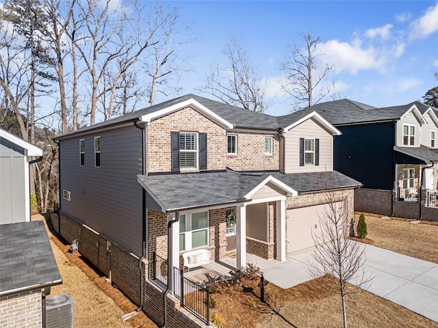 traditional-style house with brick siding, fence, a porch, central AC, and driveway