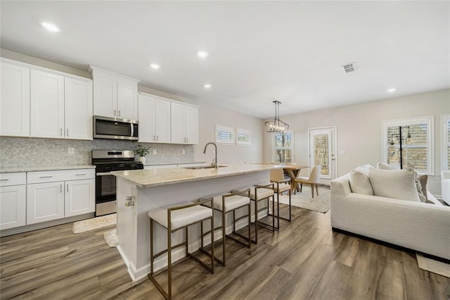 kitchen featuring wood finished floors, visible vents, a sink, white cabinets, and appliances with stainless steel finishes