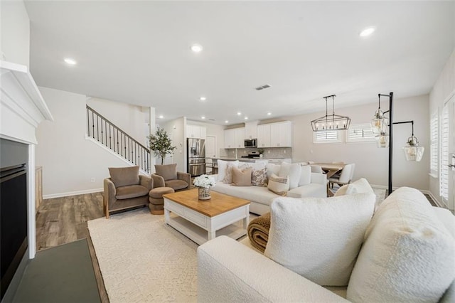 living room with recessed lighting, a fireplace, stairs, and wood finished floors