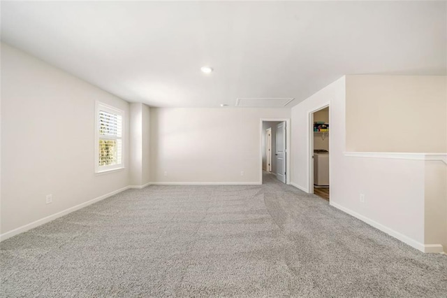 carpeted empty room featuring baseboards, washer / clothes dryer, and attic access