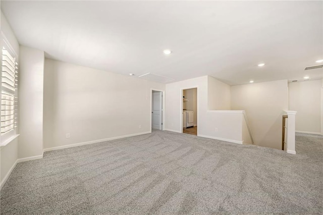 empty room featuring baseboards, attic access, carpet flooring, recessed lighting, and washer / dryer