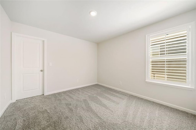 carpeted spare room featuring baseboards