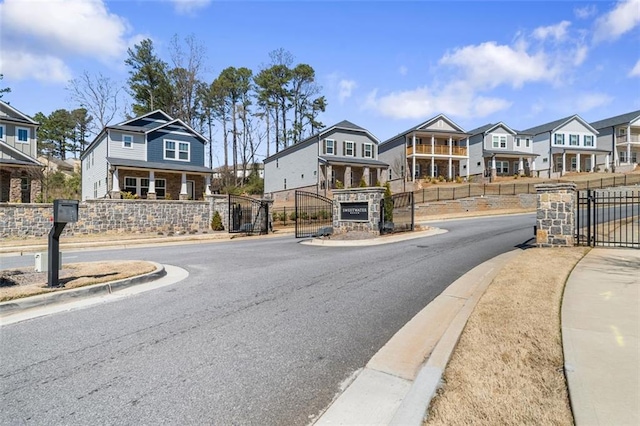 view of road with curbs, a gate, a gated entry, a residential view, and sidewalks