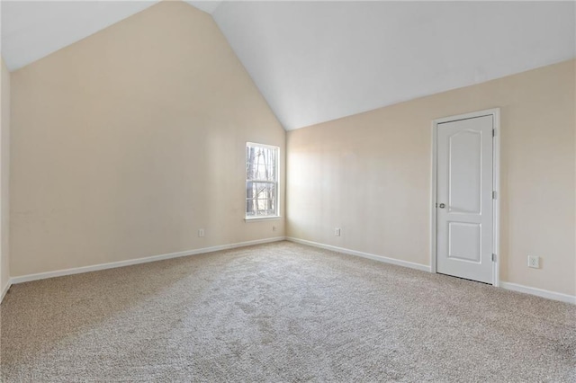 carpeted empty room with high vaulted ceiling and baseboards