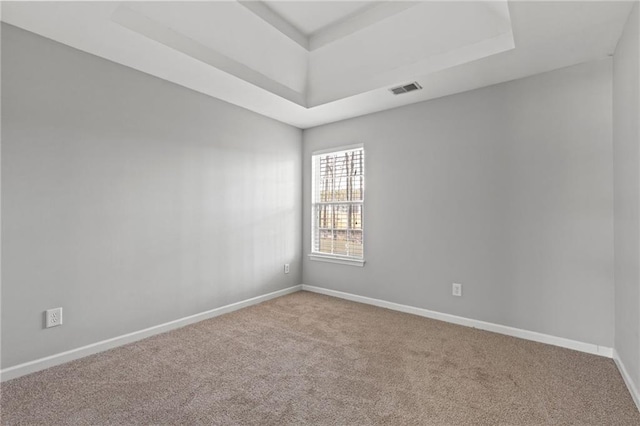 unfurnished room featuring carpet floors, a raised ceiling, visible vents, and baseboards