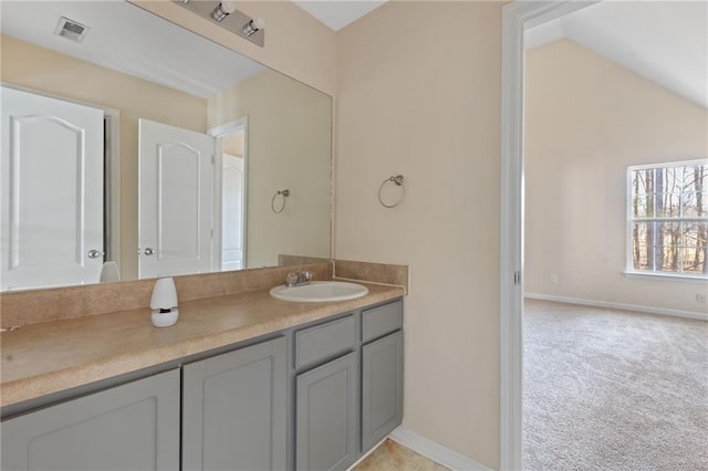 bathroom with lofted ceiling, vanity, visible vents, and baseboards