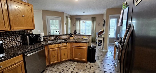 kitchen featuring sink, decorative light fixtures, backsplash, stainless steel appliances, and dark stone countertops