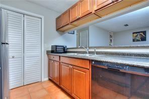 586 Windchase Ln, Stone Mountain, GA 30083 - kitchen with light countertops, brown cabinets, freestanding refrigerator, light tile patterned flooring, and a sink