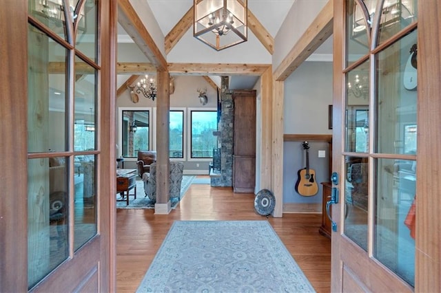 foyer with lofted ceiling with beams, a notable chandelier, and light hardwood / wood-style flooring