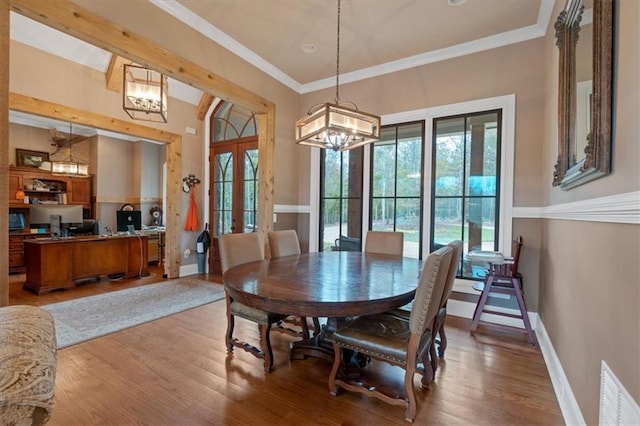 dining room featuring french doors, a notable chandelier, ornamental molding, and light hardwood / wood-style flooring