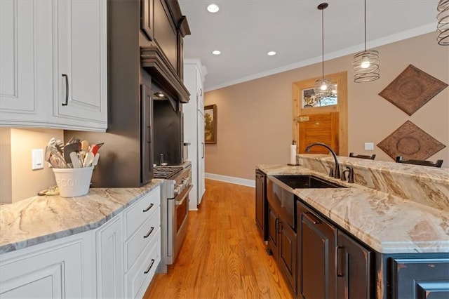 kitchen with white cabinets, high end stainless steel range oven, dark brown cabinets, and light wood-type flooring