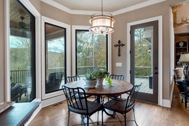 dining space with wood-type flooring, a chandelier, and crown molding