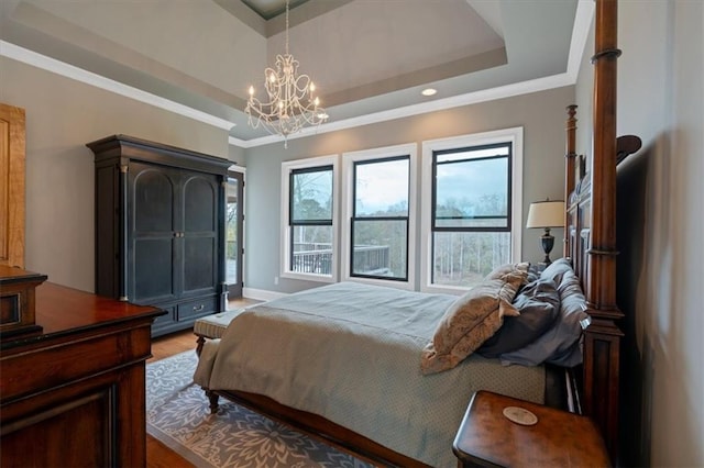 bedroom with hardwood / wood-style floors, a raised ceiling, an inviting chandelier, and crown molding