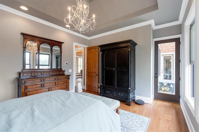 bedroom with light wood-type flooring, multiple windows, an inviting chandelier, and a raised ceiling