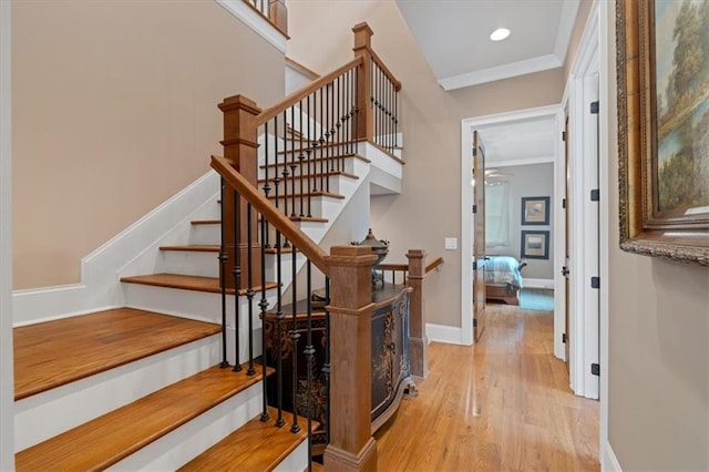 stairway with wood-type flooring and crown molding