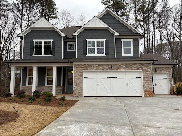 craftsman inspired home featuring an attached garage, covered porch, stone siding, and concrete driveway