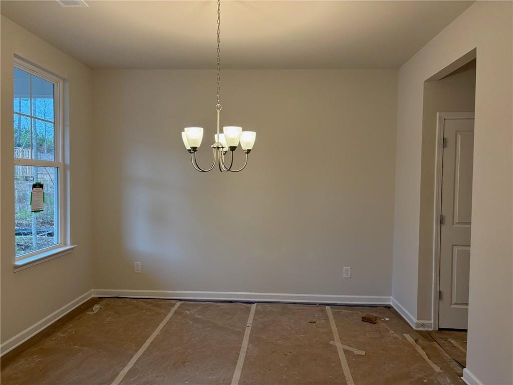 unfurnished room featuring a notable chandelier and baseboards