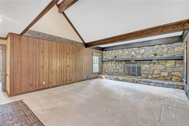 unfurnished living room with beamed ceiling, wood walls, a stone fireplace, and baseboards
