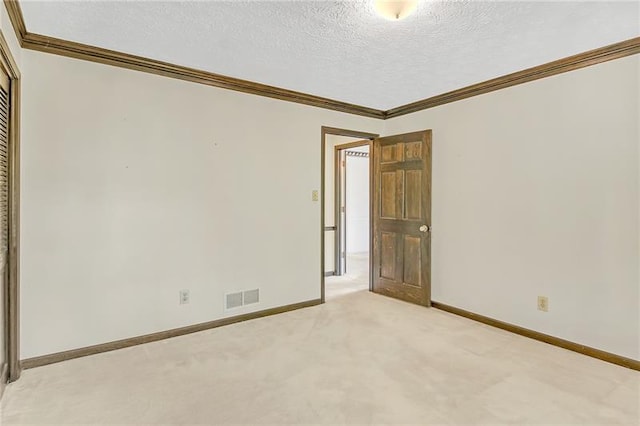unfurnished room with visible vents, ornamental molding, baseboards, light colored carpet, and a textured ceiling