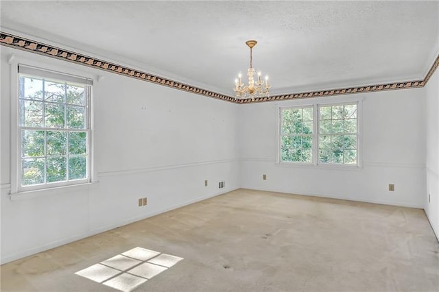 spare room featuring an inviting chandelier, carpet, and a healthy amount of sunlight