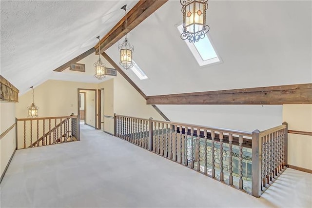 additional living space with visible vents, baseboards, lofted ceiling with skylight, an inviting chandelier, and carpet flooring