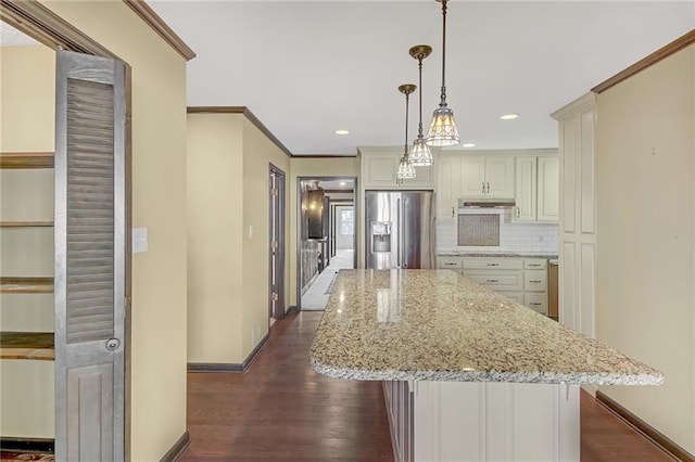 kitchen with a kitchen island, dark wood finished floors, stainless steel fridge with ice dispenser, baseboards, and under cabinet range hood