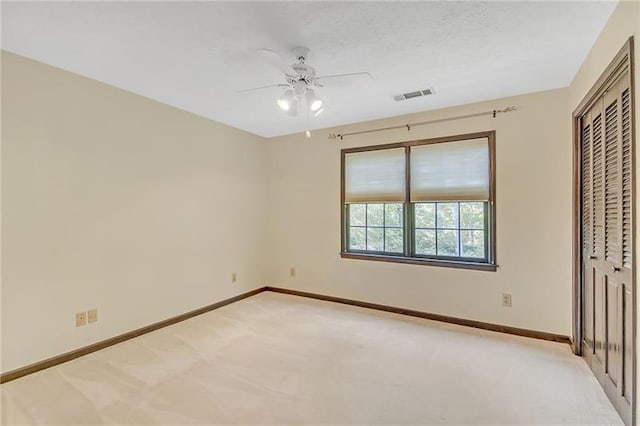 unfurnished bedroom featuring a closet, baseboards, light colored carpet, and visible vents